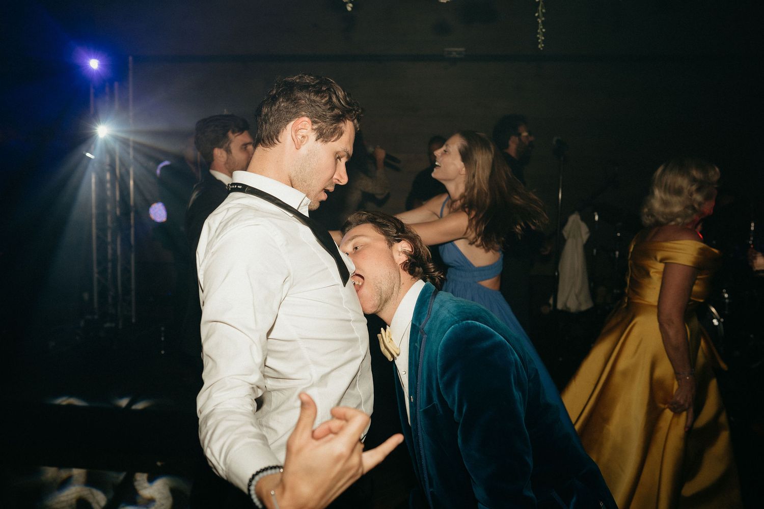People dancing together in a dimly lit nightclub with blue lighting and atmospheric effects.