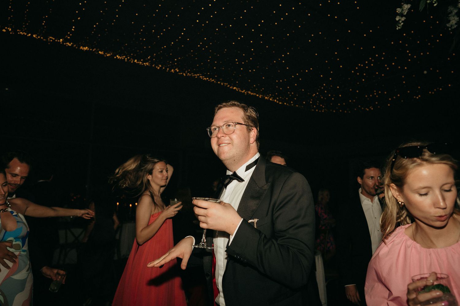 People dancing and enjoying themselves at a formal event under dim lighting with a sparkly ceiling.