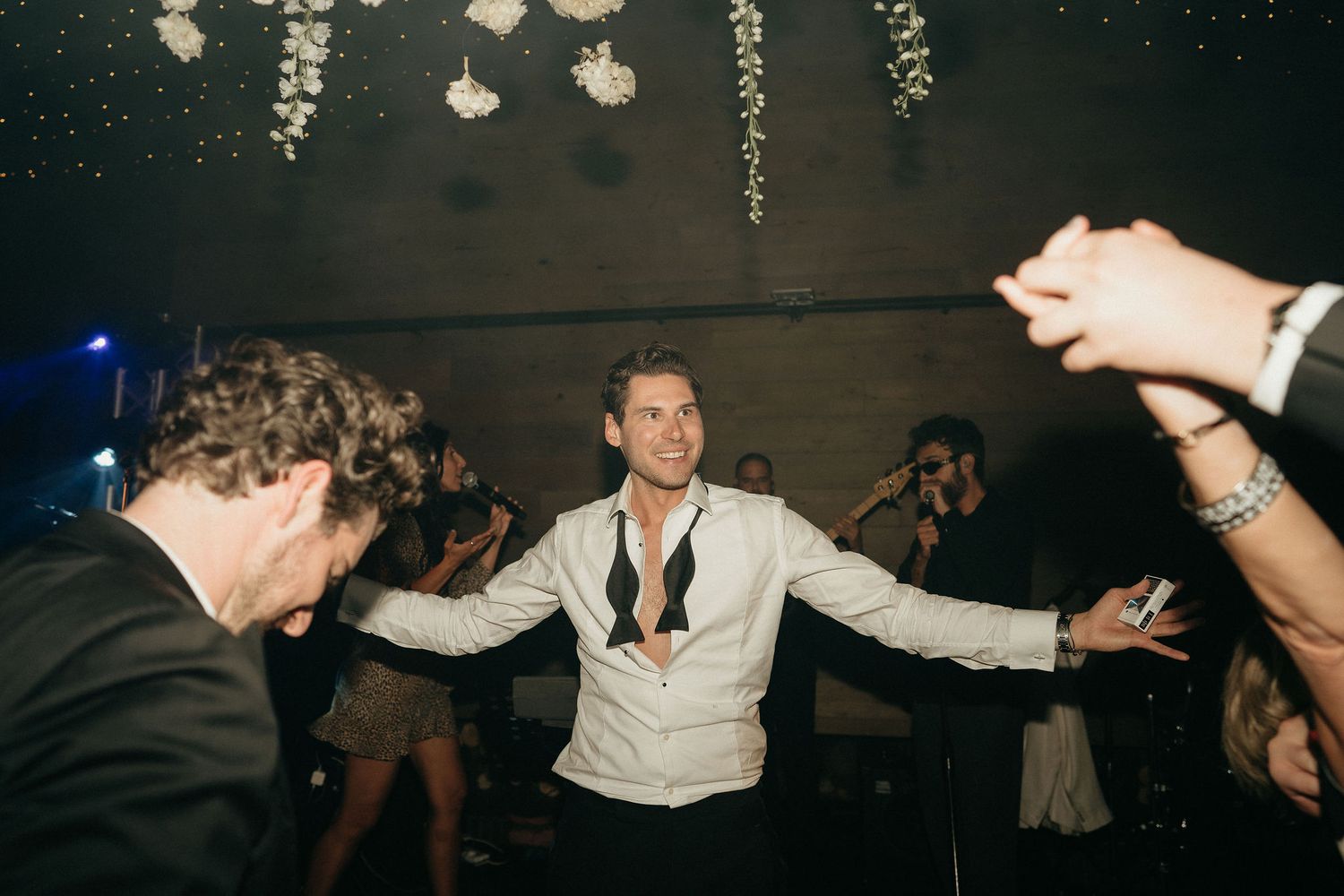 A group of people dancing and socializing at a dimly lit party or nightclub event.