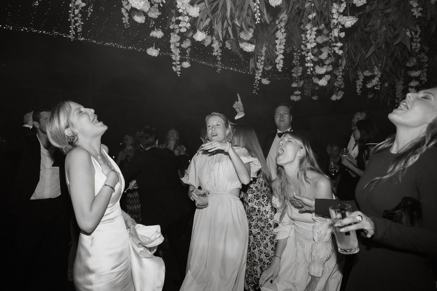 Black and white photos of wedding guests dancing and celebrating at a reception party on the dance floor.
