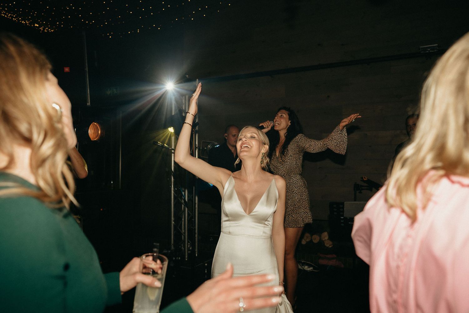 People dancing and celebrating at a nighttime wedding reception with dramatic lighting effects.