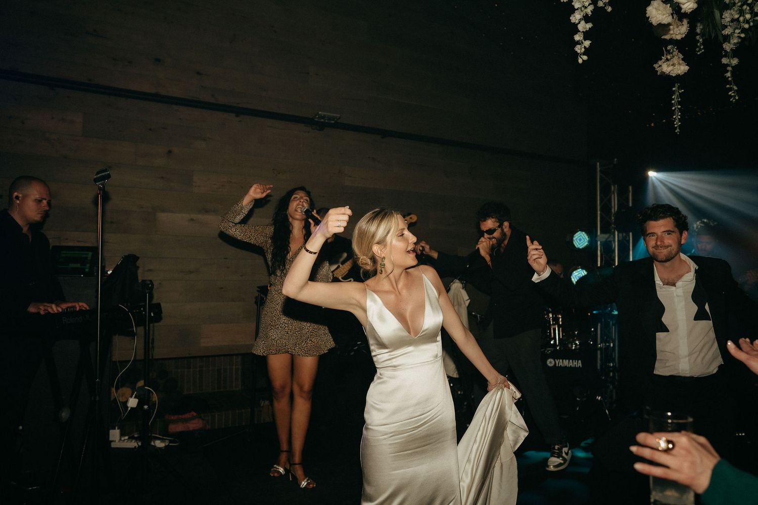 A bride and groom share their first dance at a wedding reception while guests look on in a dimly lit venue.