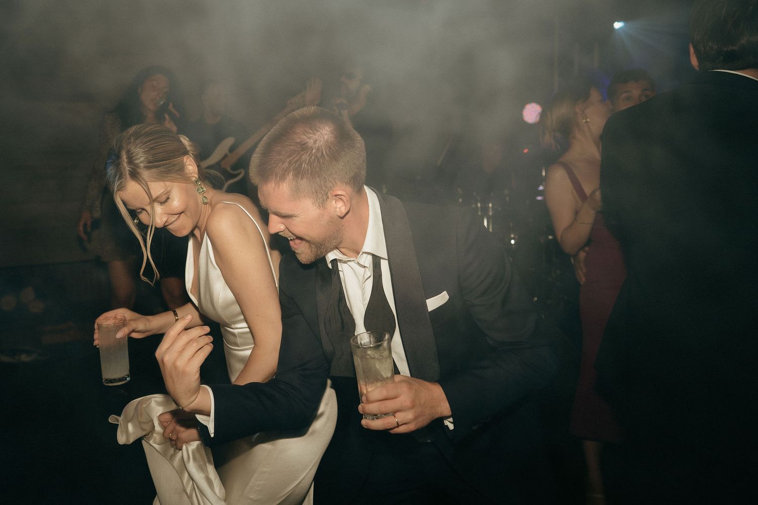A couple shares an intimate dance moment at a dimly lit wedding reception.