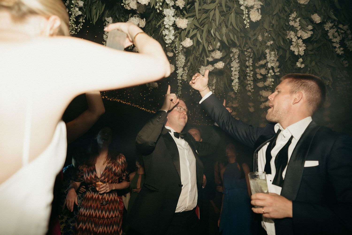 A group of people dancing and celebrating at an elegant evening event in a dimly lit venue.