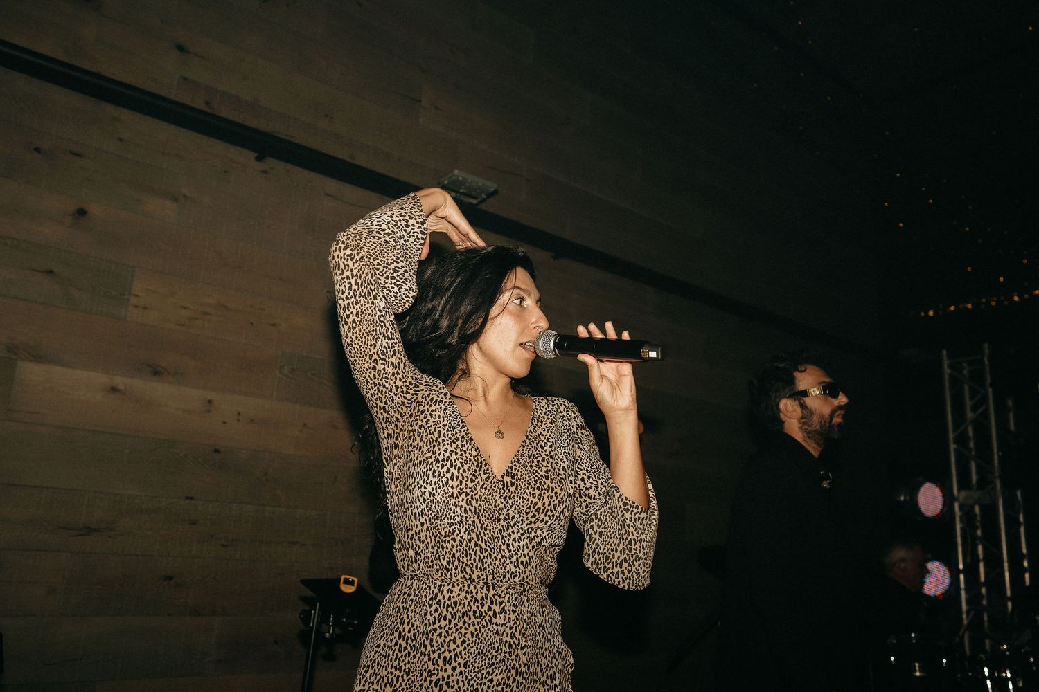 A person in a leopard print dress performs on stage with dramatic lighting and expressive movements.