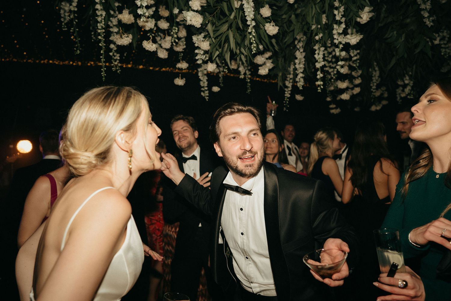 People in formal attire socialize and celebrate at an elegant evening wedding reception.