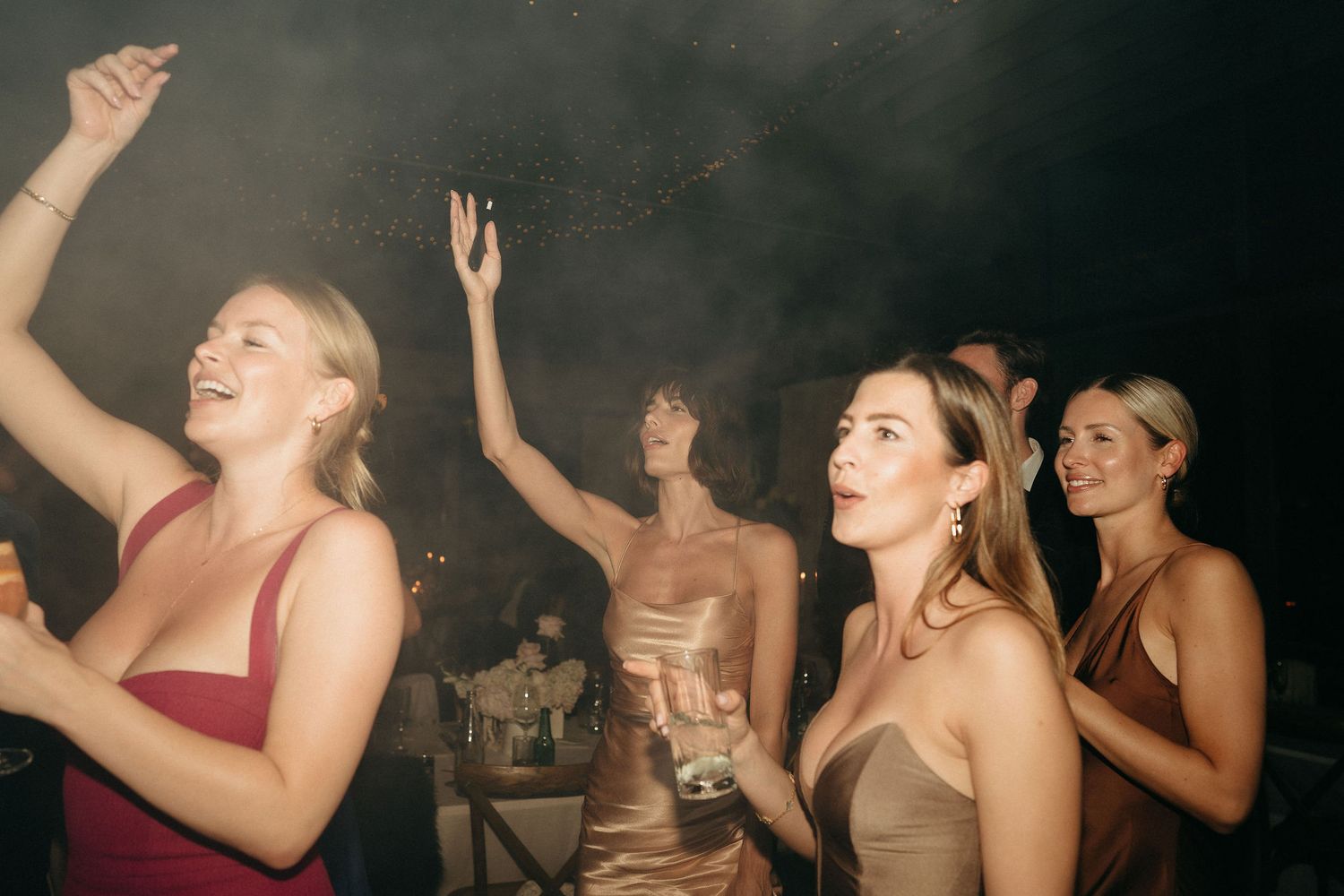 People dancing and enjoying themselves at a nightclub or party with dim lighting and energetic atmosphere.