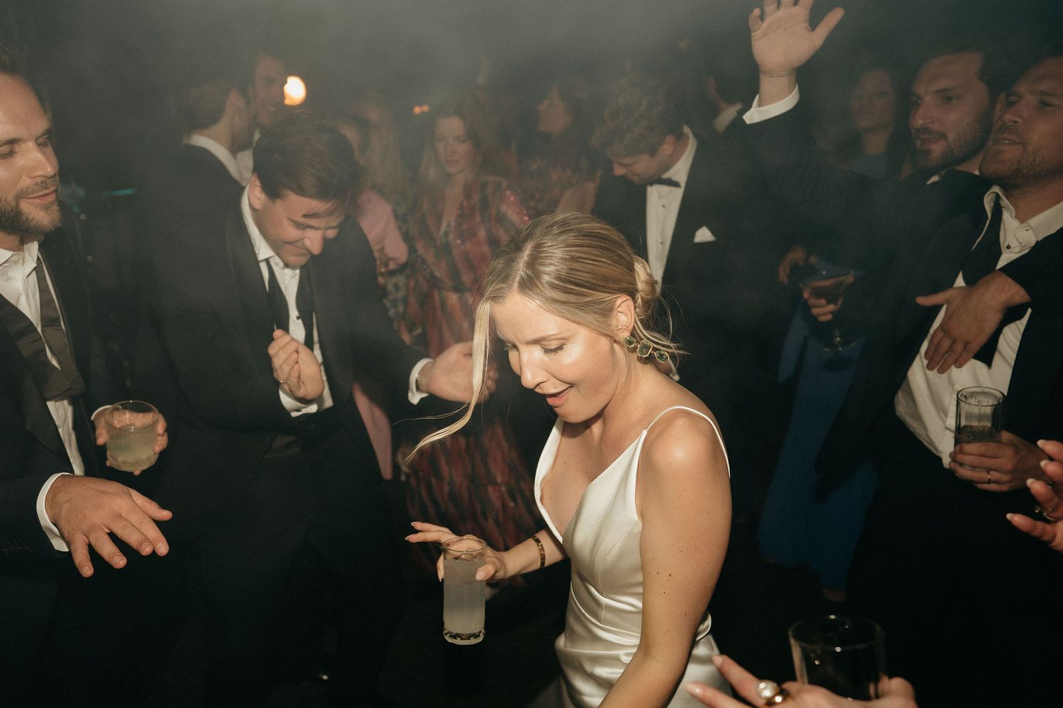 A group of people dancing and celebrating at a lively party in a dimly lit room.