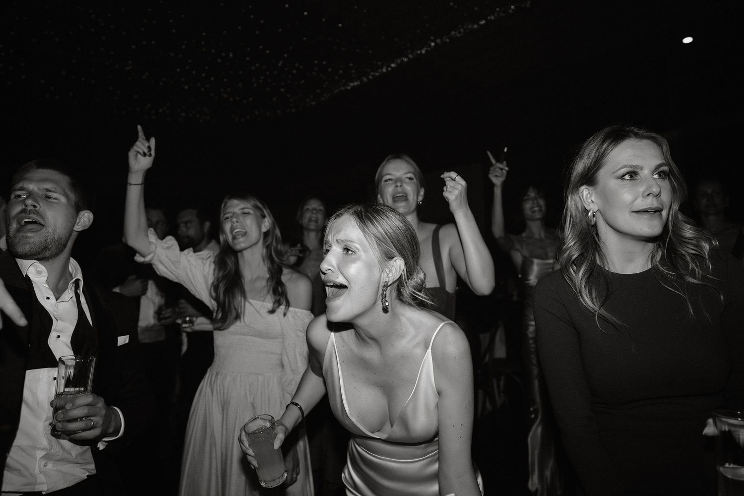 A black and white collage of candid dance floor moments at a wedding reception.