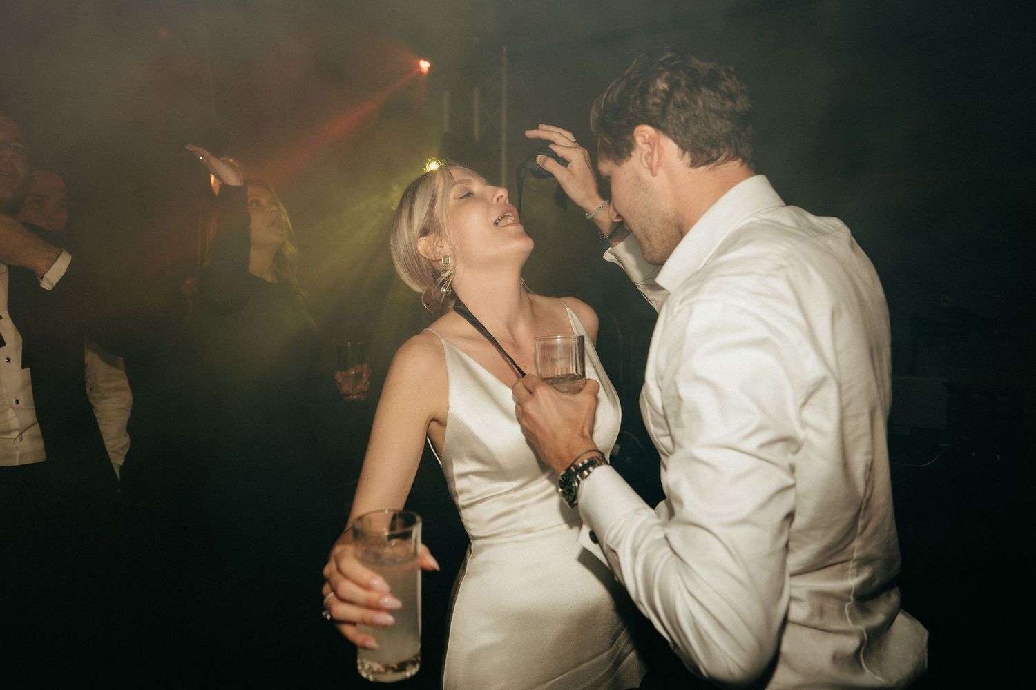 Couples dancing intimately at a dimly lit wedding reception with romantic lighting and shadows.