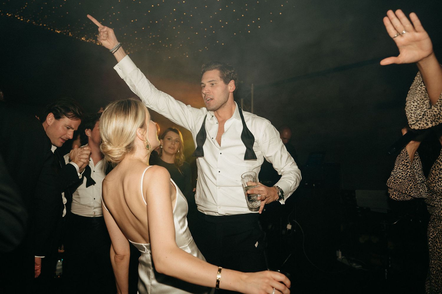 People dancing and having fun at a dark nightclub or party venue with atmospheric lighting.