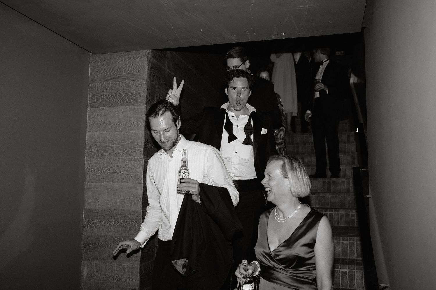Black and white photo of people dancing and celebrating at what appears to be a wedding reception or party.