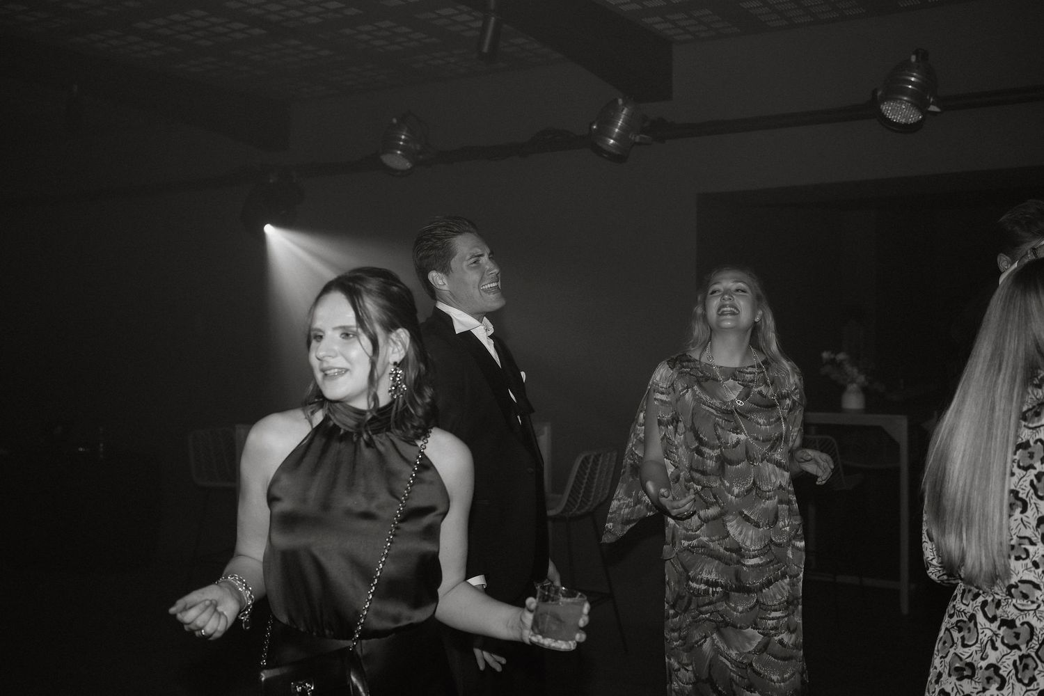 A group of people dancing and socializing at a dimly lit party or nightclub venue.