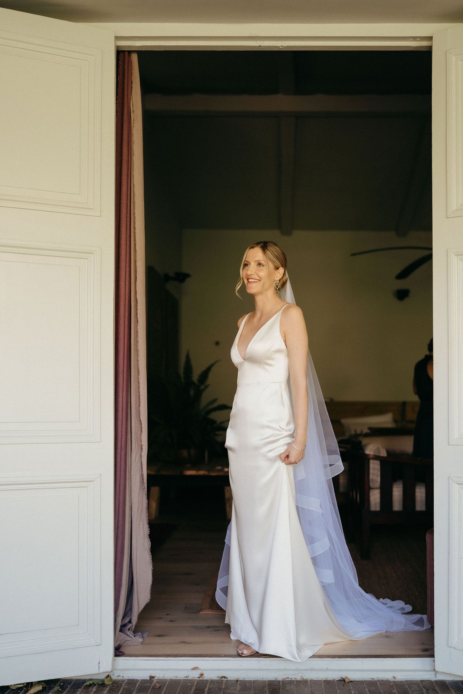 A series of elegant white wedding dress shots framed through doorways in a bright interior setting.