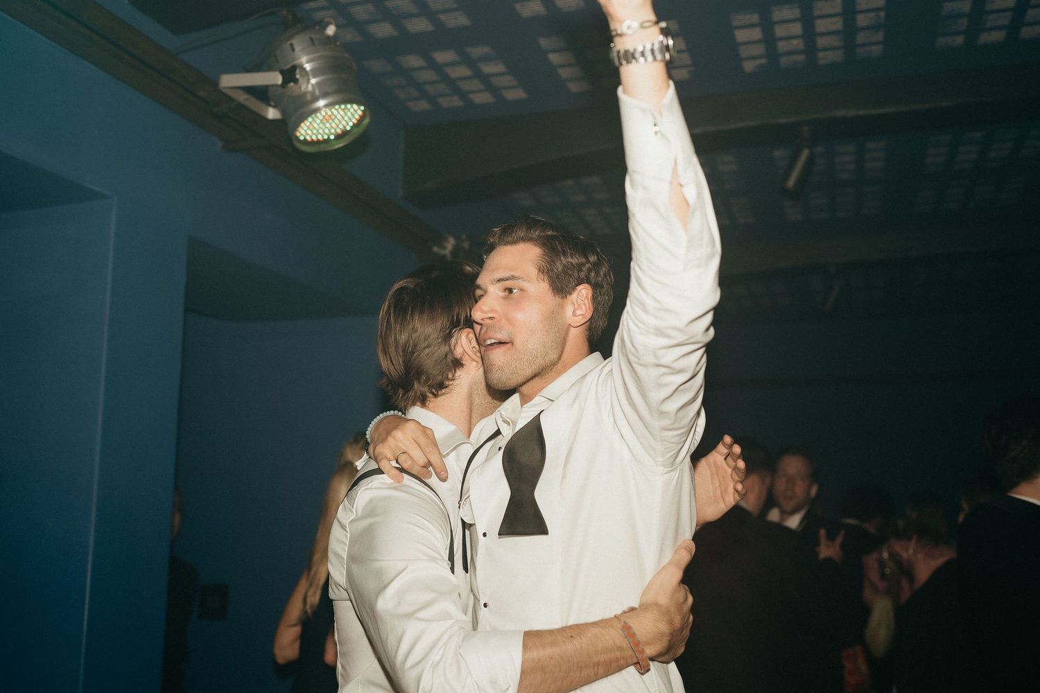 Couple dancing together in a dimly lit venue during what appears to be a wedding celebration.