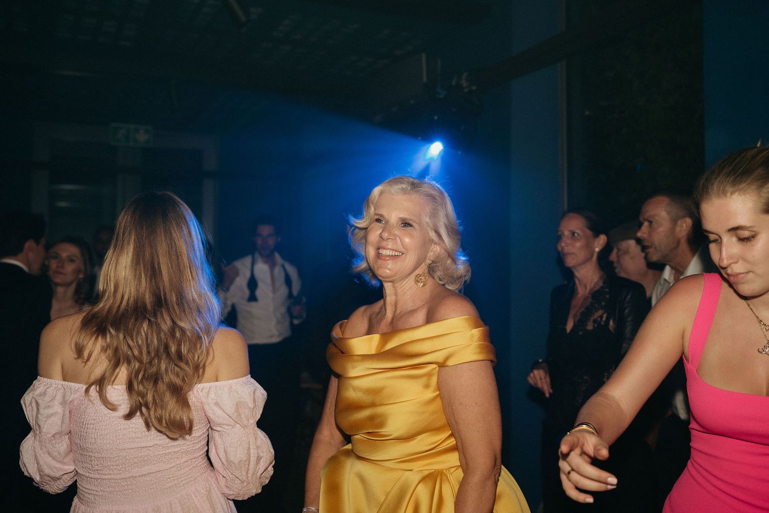 People dancing and enjoying themselves at a nightclub with blue lighting and dark atmosphere.