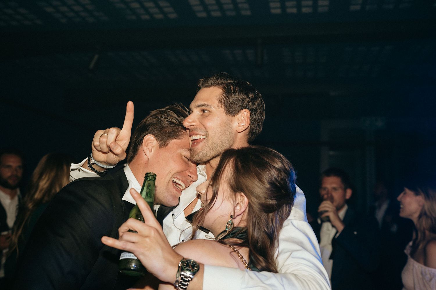 A couple embraces in a tender moment during their wedding celebration surrounded by guests.