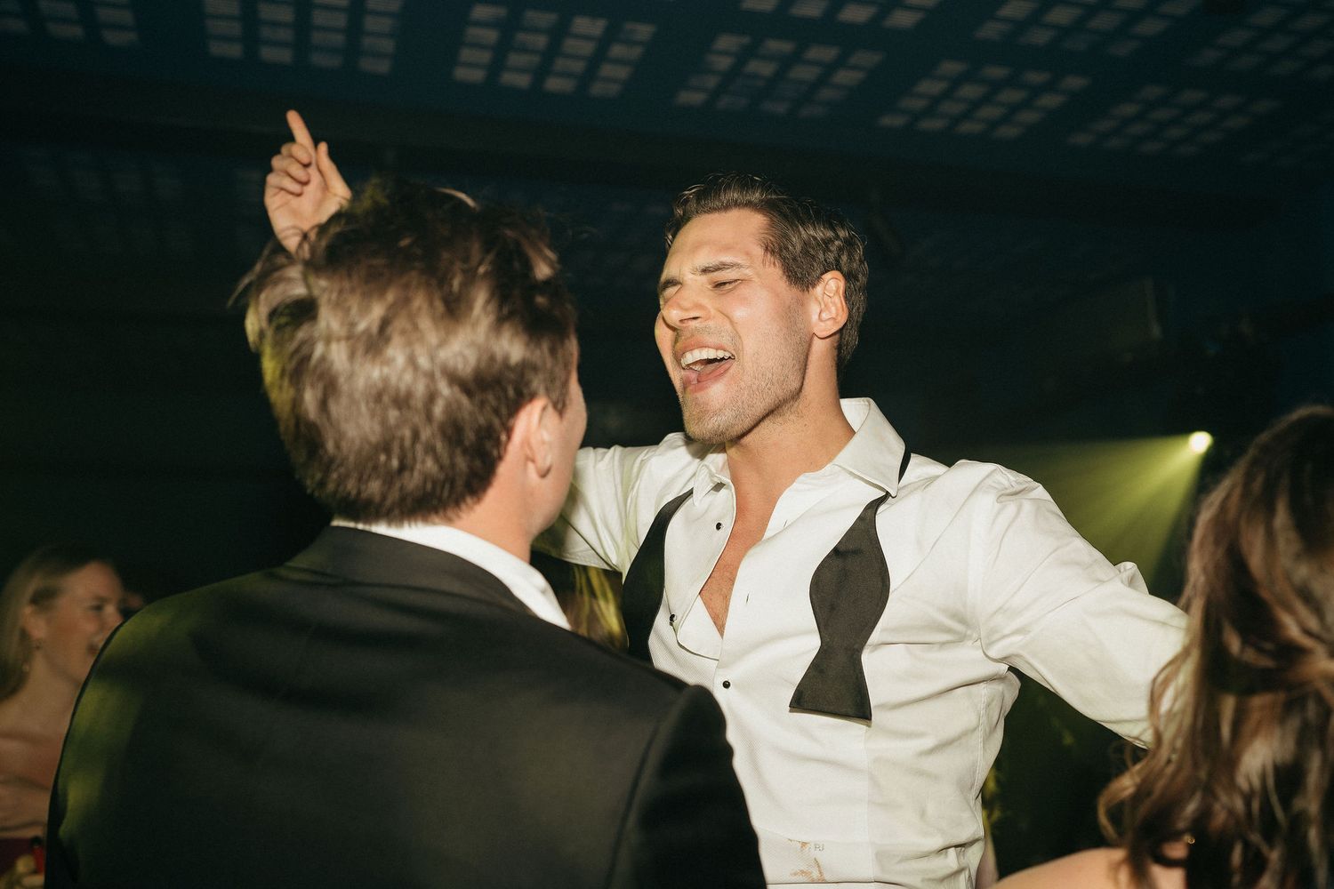People dancing and celebrating at a lively party in a dimly lit venue.
