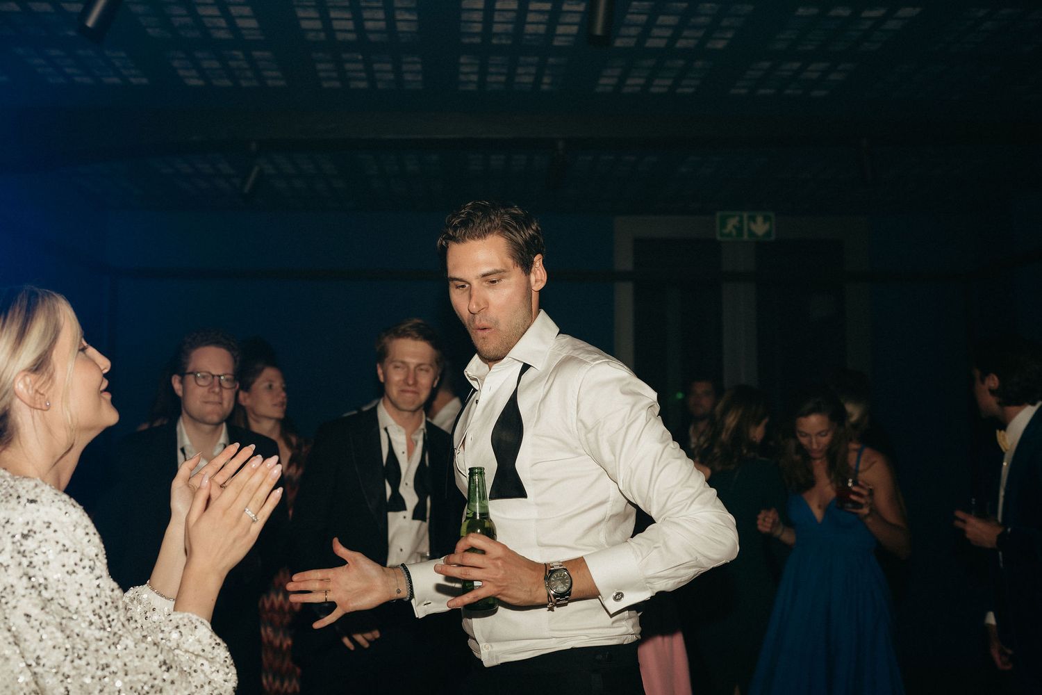 Wedding reception dance floor filled with guests enjoying themselves under blue ambient lighting.