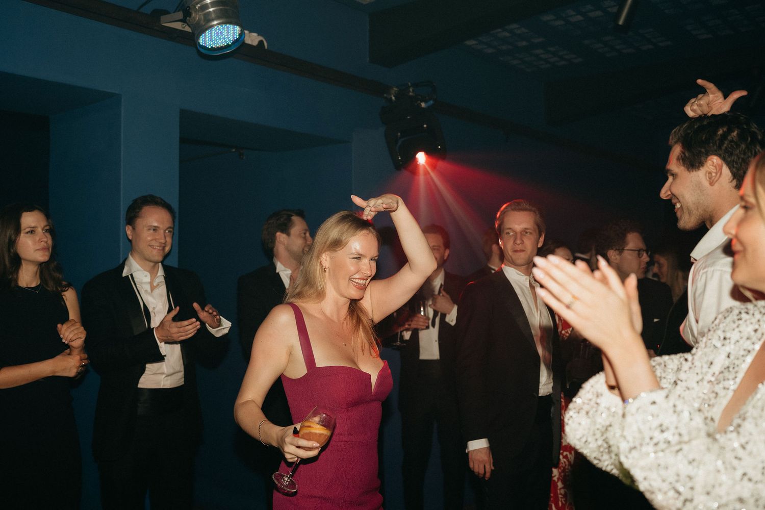 Guests dance and celebrate at an elegant wedding reception with burgundy and formal attire.