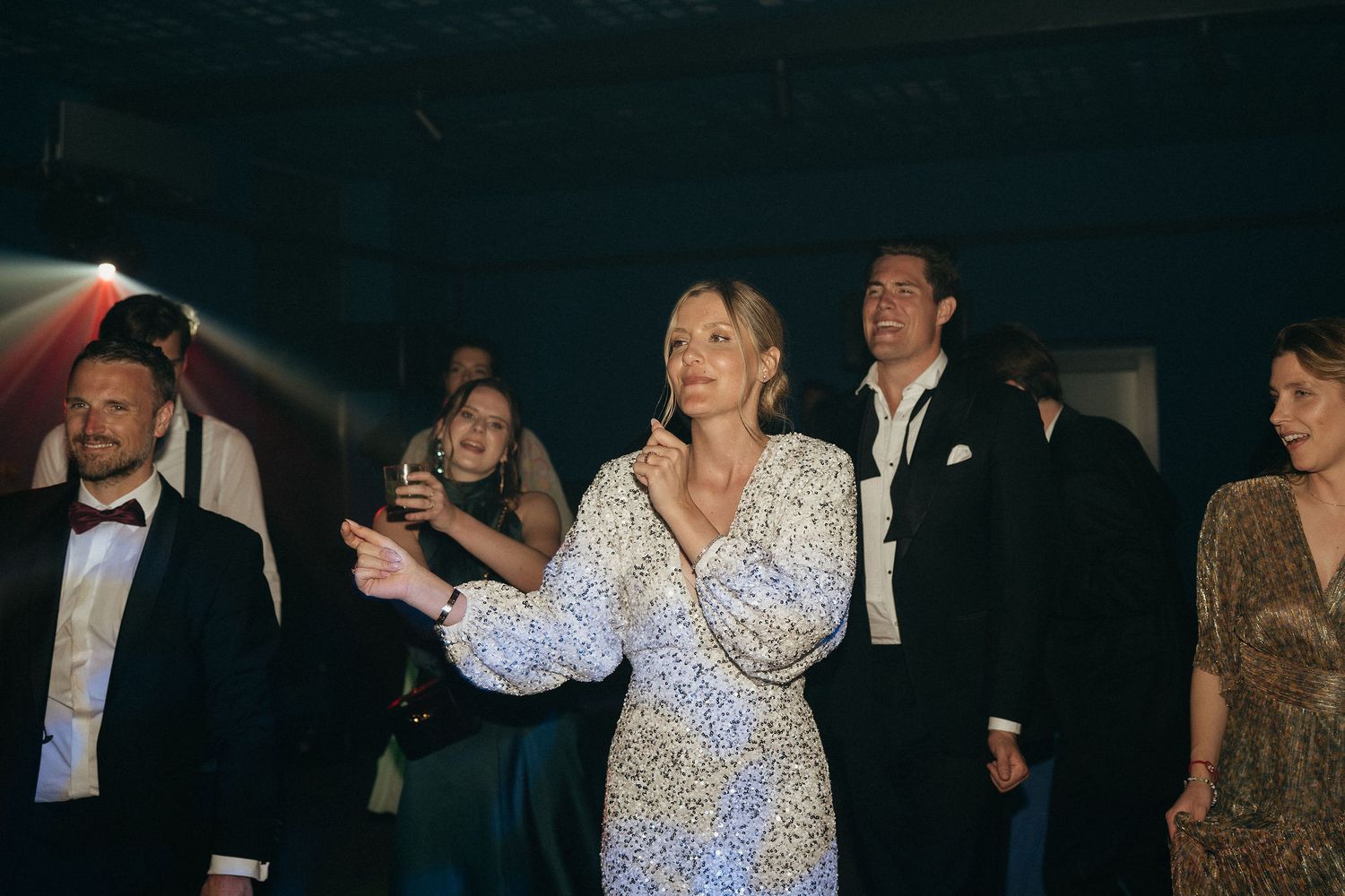 People dancing and enjoying themselves at a formal event in a dimly lit venue.