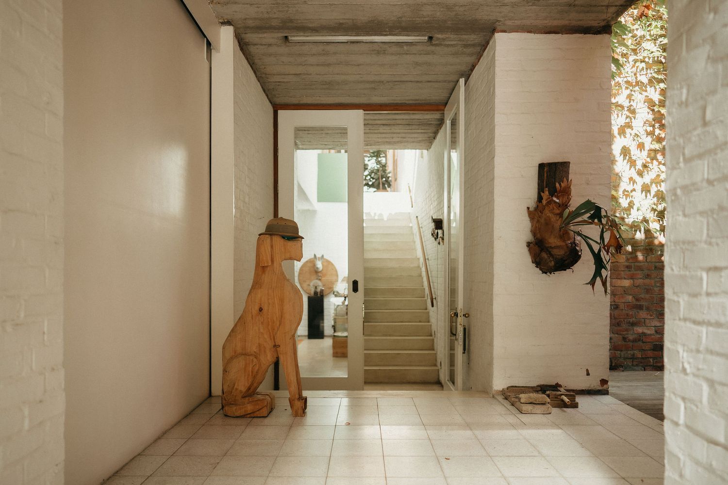 Long white corridor with terracotta dog sculptures placed along a minimalist interior hallway.