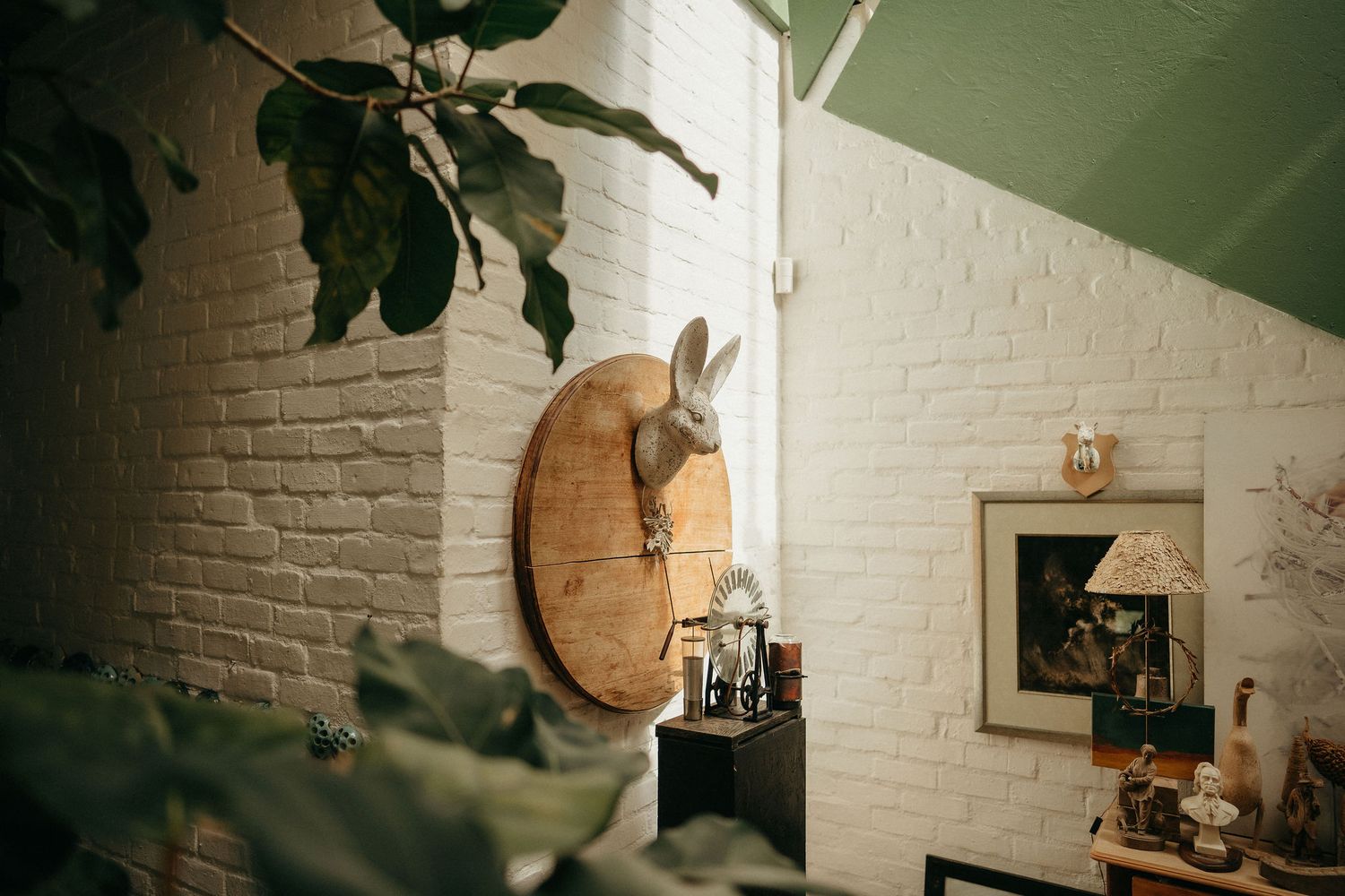 Rustic white brick wall decorated with wooden clock and vintage artwork in a cozy interior setting.