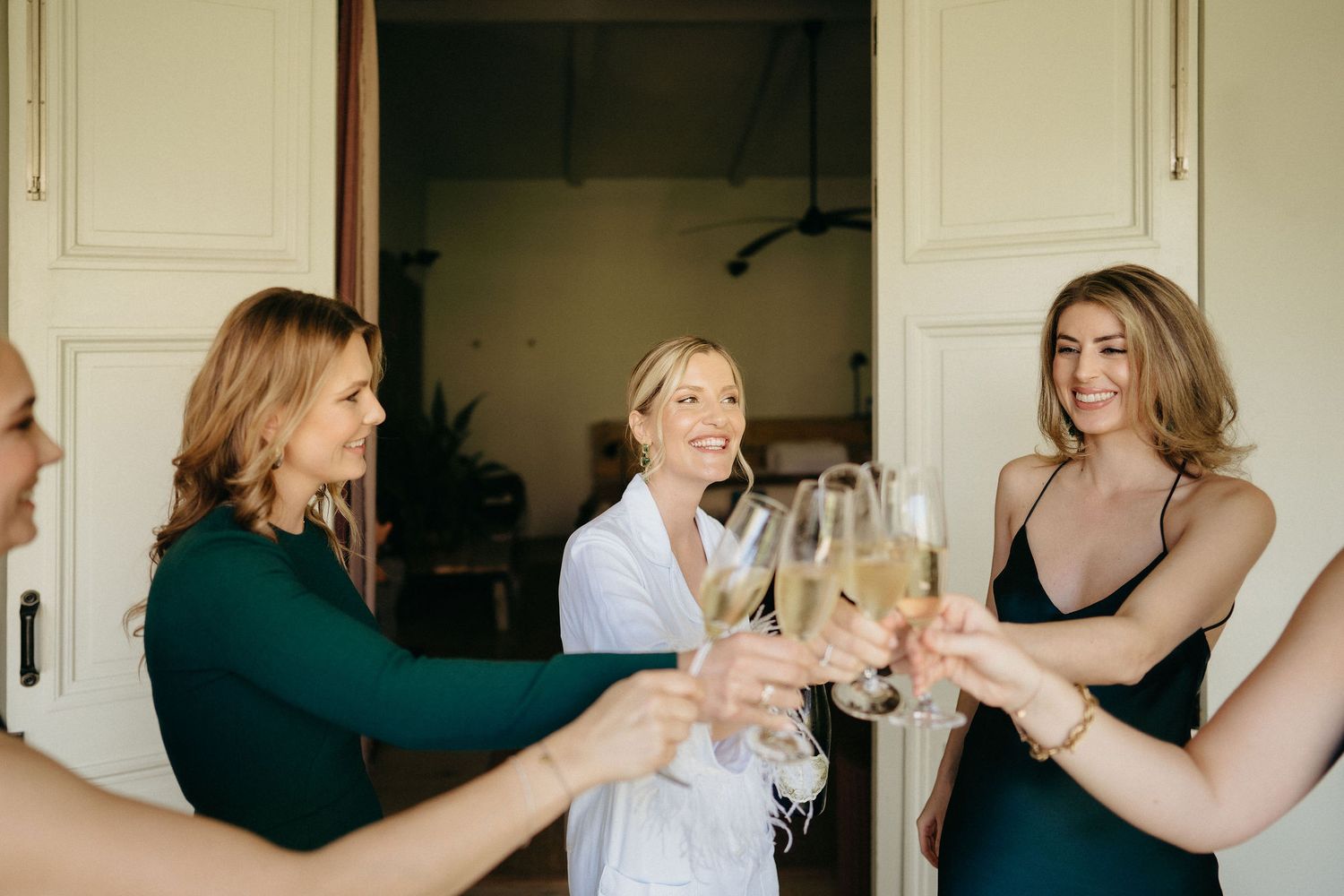 People raising champagne glasses in a toast during a celebratory moment indoors.