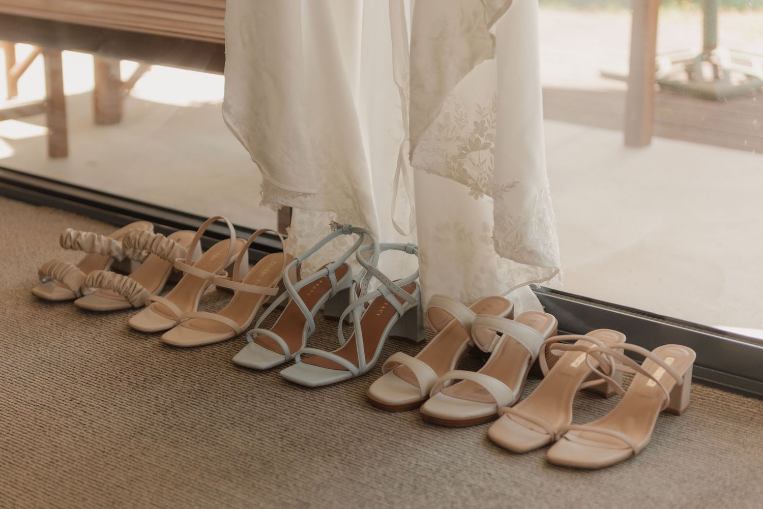 Colorful summer dresses hanging on wooden hangers against a bright outdoor backdrop with greenery.