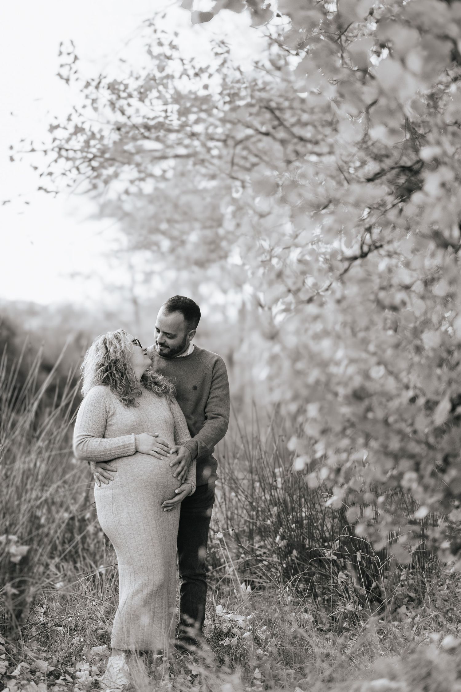 A romantic couple shares tender moments together in a dreamy outdoor setting with blooming spring trees.