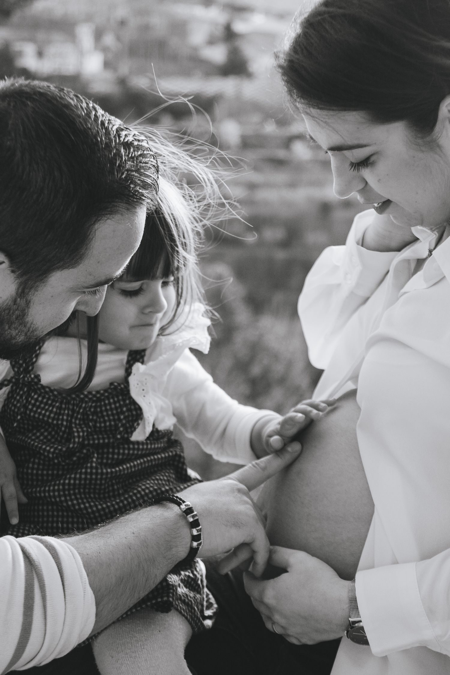Black and white intimate family moment showing tender interaction between couple with newborn.