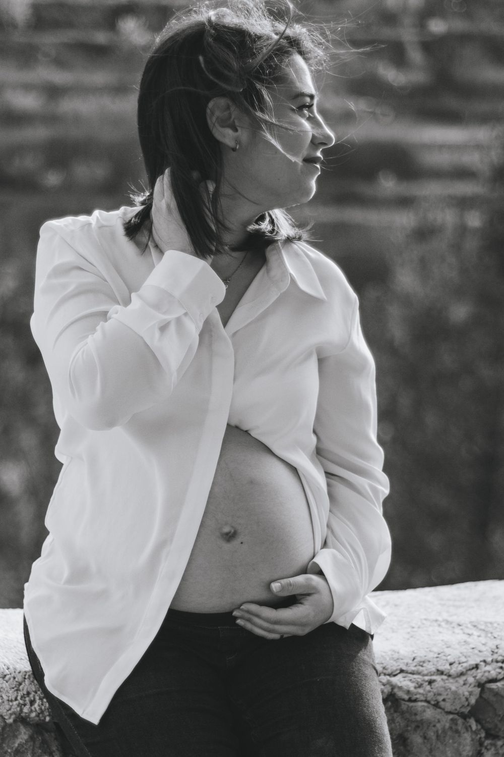 Artistic black and white portrait series of person in white blouse against stone background.