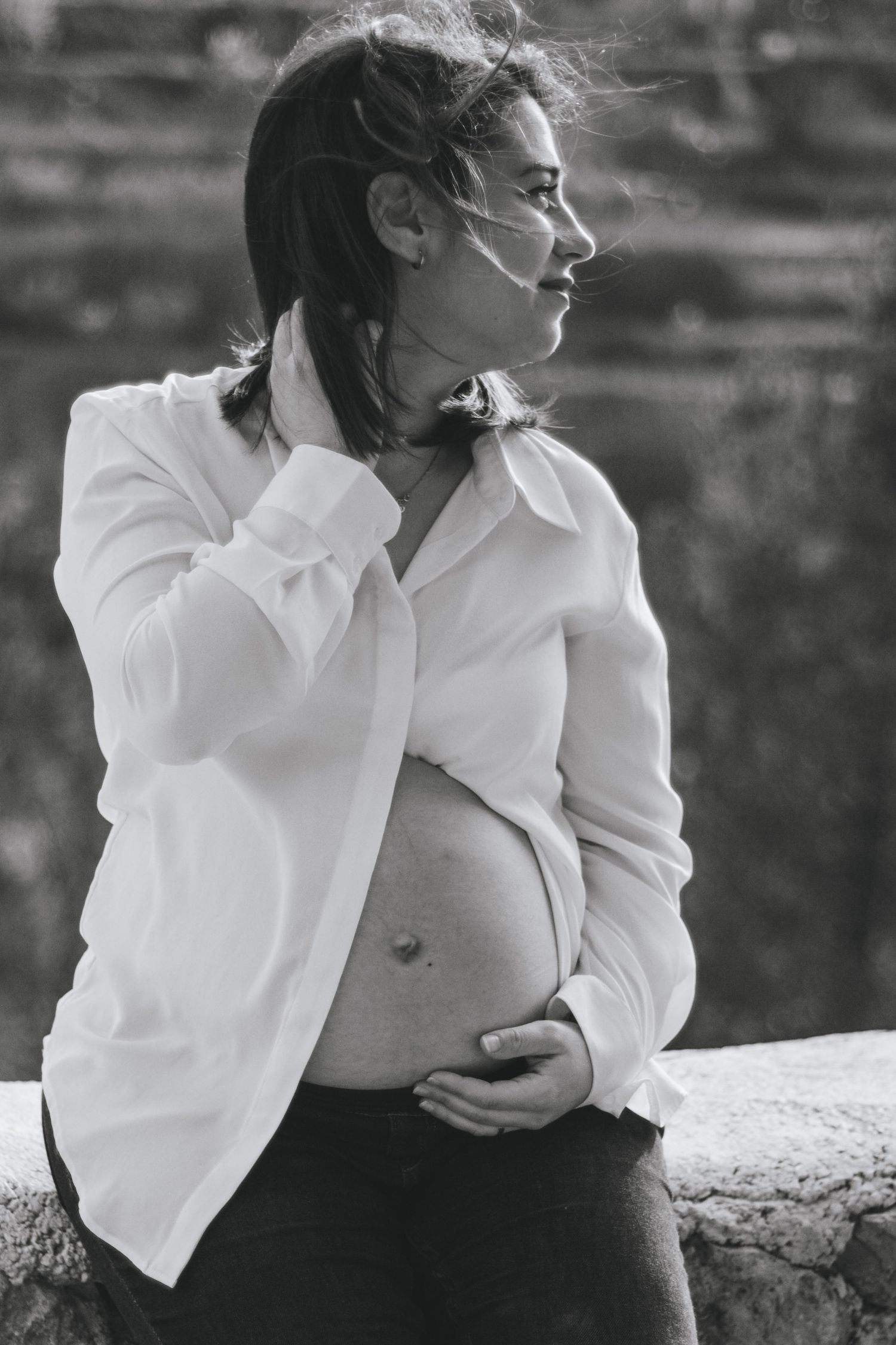 Artistic black and white portrait series of person in white blouse against stone background.
