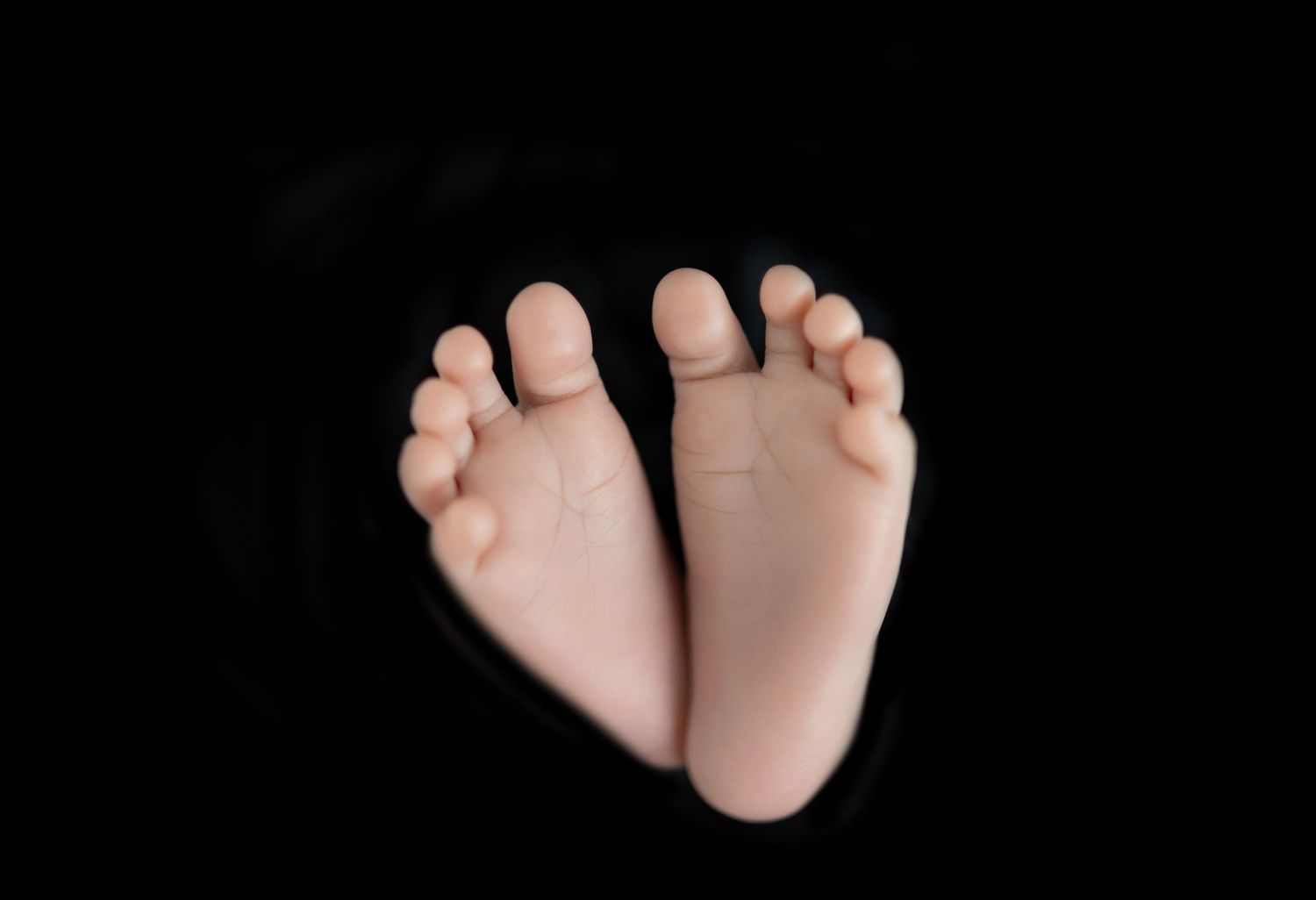 Seven black and white photographs arranged in a row showing baby feet and toes from different angles.