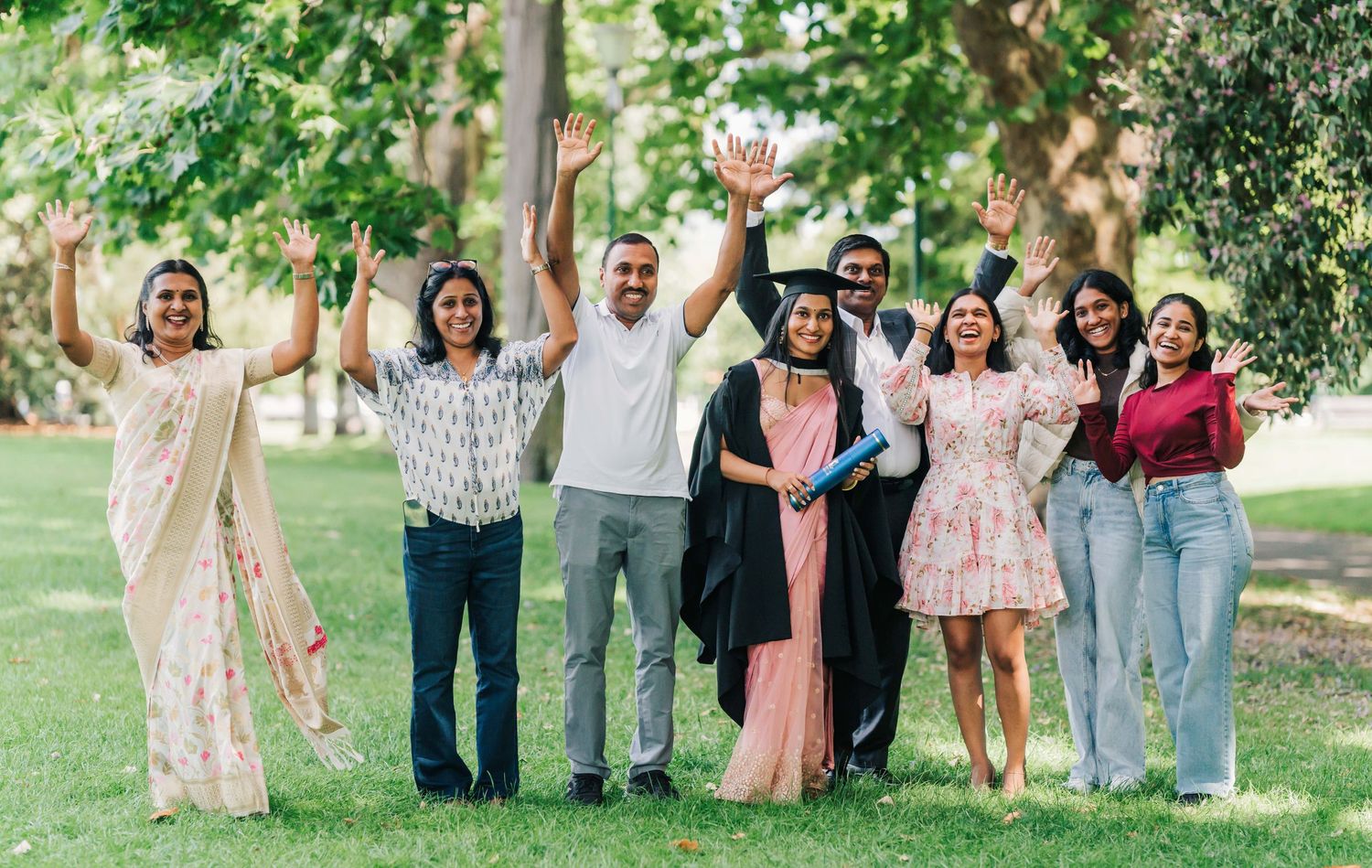 A series of outdoor group photos showing people in coordinated pastel and neutral outfits posing together in a garden setting.