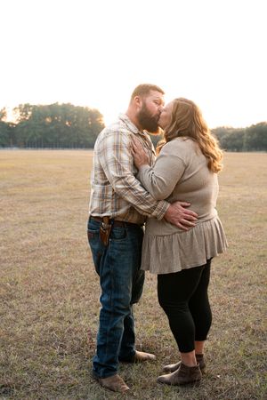 A romantic couple embraces in a sunlit field during golden hour, creating a series of intimate poses.