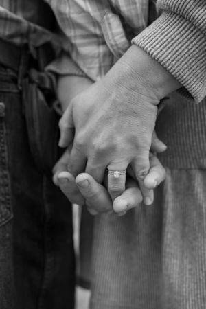 A series of black and white photographs showing two hands clasped together, with one hand wearing a ring.