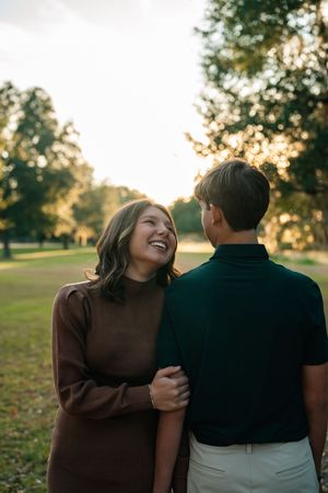 A couple shares a joyful moment together in a park during golden hour sunset.