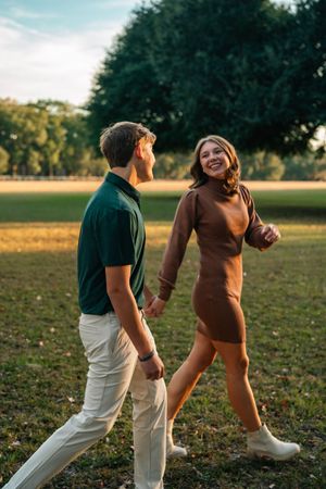 Two people dance together playfully in a grassy field at sunset, creating joyful movement and laughter.