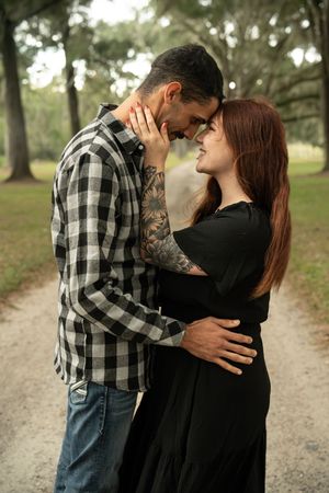 Intimate moment between couple on a nature path wearing casual clothing.