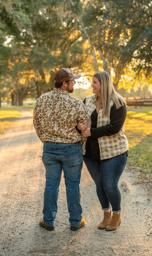 Couple embracing on a scenic gravel path during golden hour at a plantation venue.