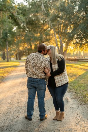 Romantic sunset photoshoot on a tree-lined gravel path at golden hour.