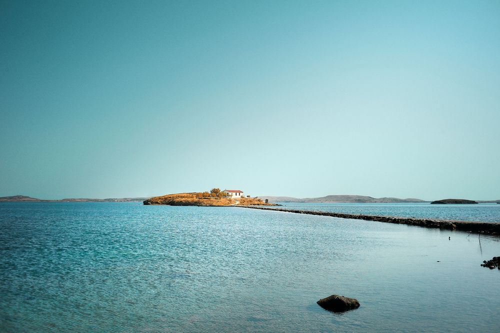 Panoramic view of a tranquil blue sea with distant islands and coastal landscape under clear skies.