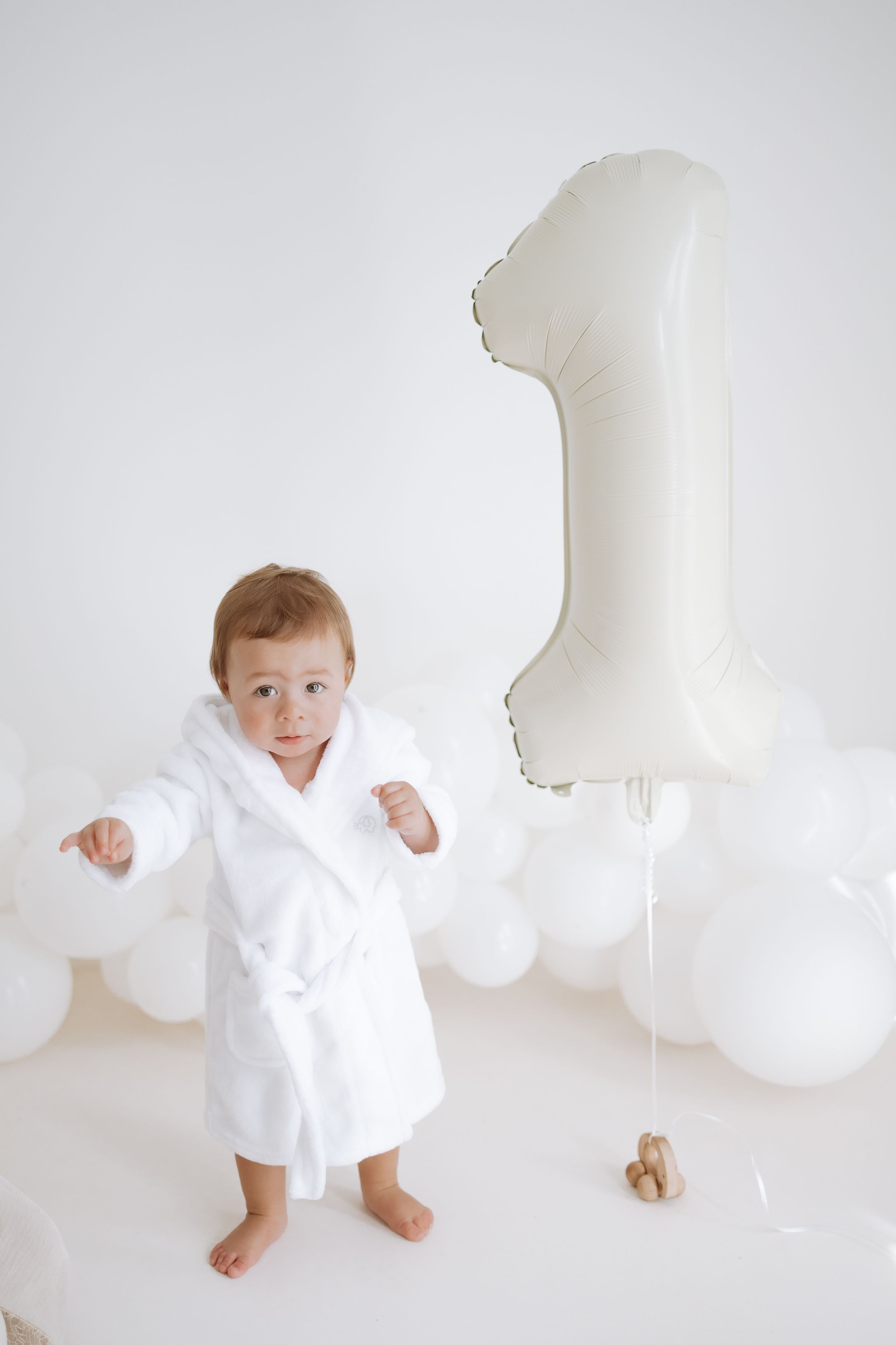 A series of four minimalist photos showing a small child in white clothing against a white background.