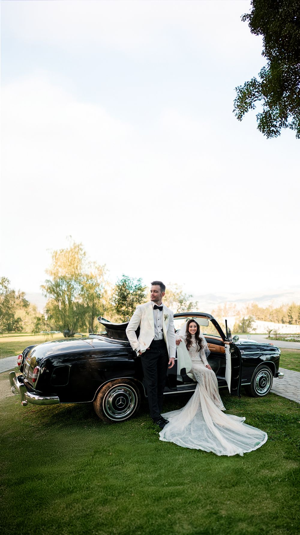 Classic car wedding photos featuring a vintage black automobile on a grassy lawn.