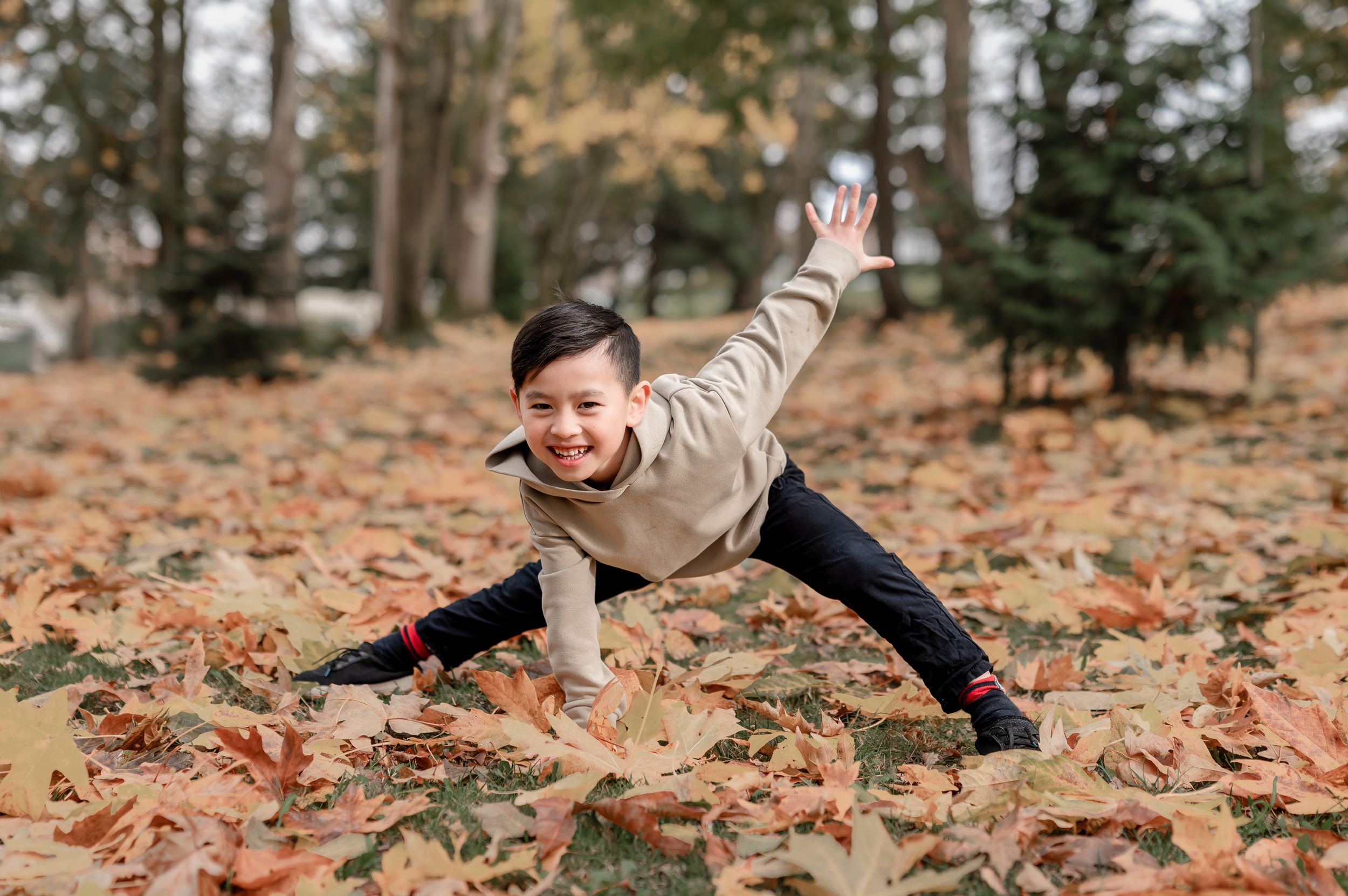 Person playfully rolling through autumn leaves on the ground in a forest during fall season.