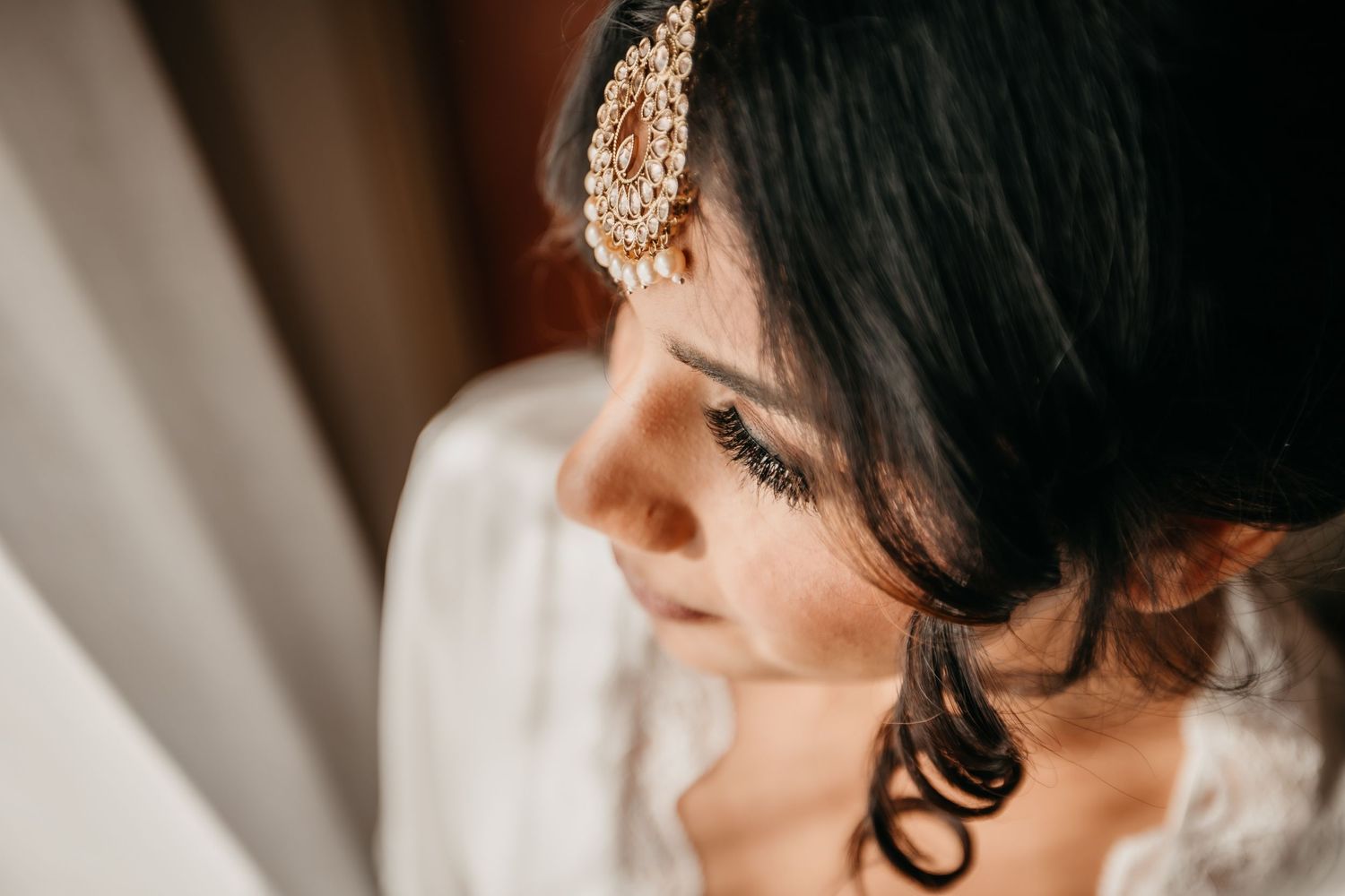 Close-up profile view of a bride wearing an ornate gold hair accessory with soft natural lighting.