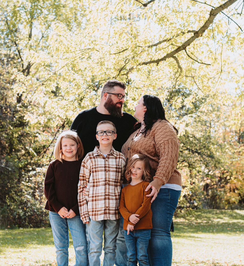 Candid family portrait of five people laughing together in fall setting.