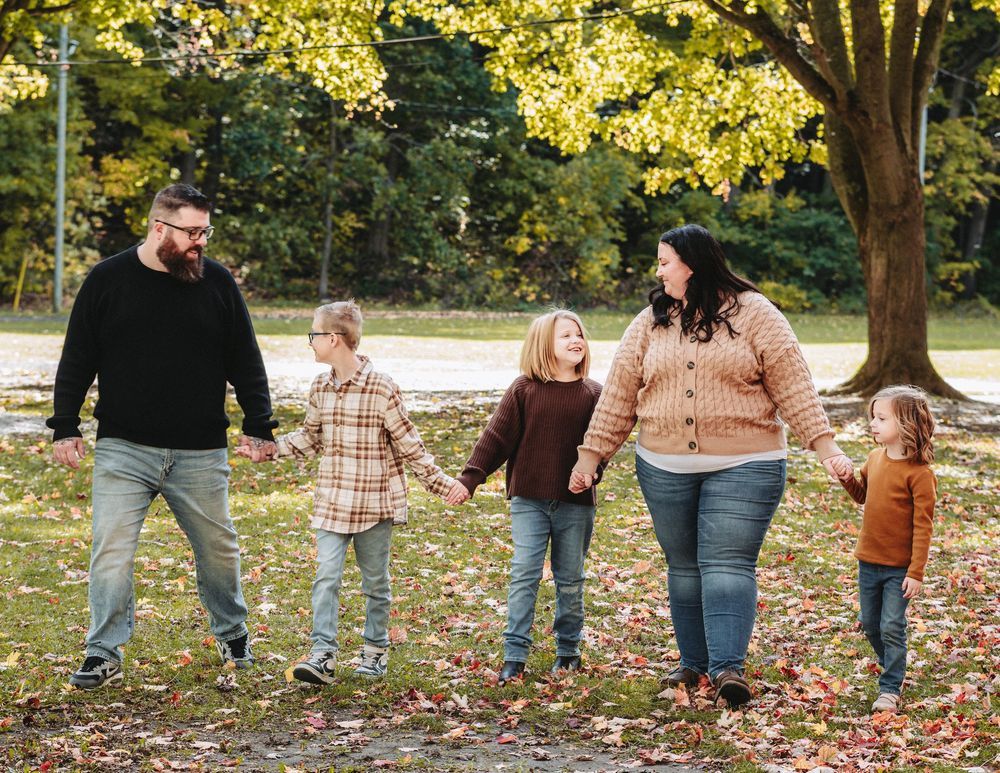 Group walking together through a sunlit park with golden fall foliage overhead.