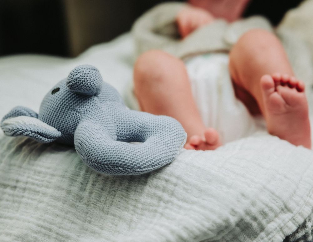 A small gray neck pillow rests on a textured white surface.